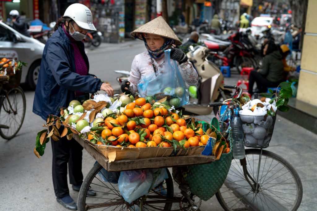 A vibrant street market scene with vendors selling fresh fruit in an urban setting.